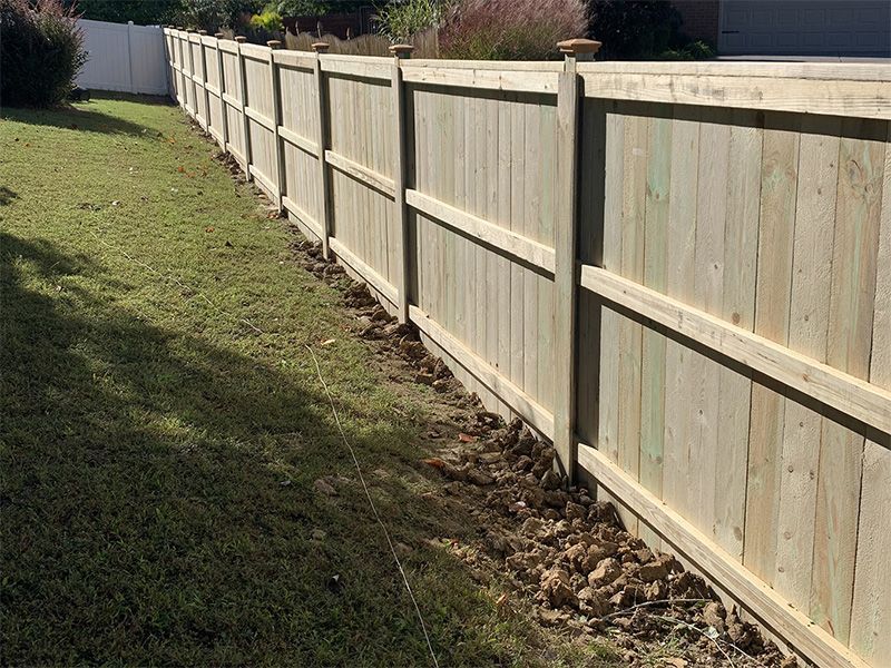 A wooden fence is sitting in the middle of a lush green yard.