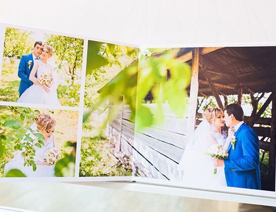 Wedding photo album with a couple in blue and white posing outdoors by a rustic building.