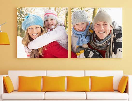 Two framed winter portraits above a white couch with orange pillows