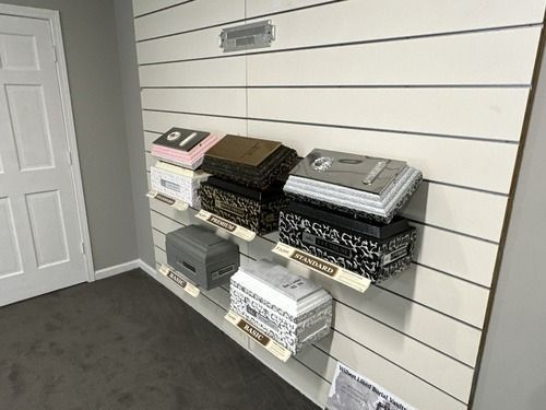Shelves of folded fabric or papers stacked on a white slat wall in a carpeted room