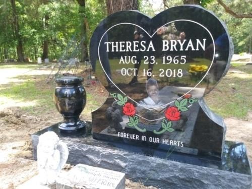 Heart-shaped black memorial headstone with red roses for Theresa Bryan in a wooded cemetery