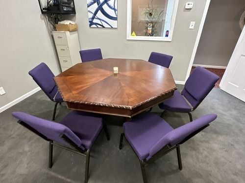 Conference room with octagonal wooden table and six purple chairs