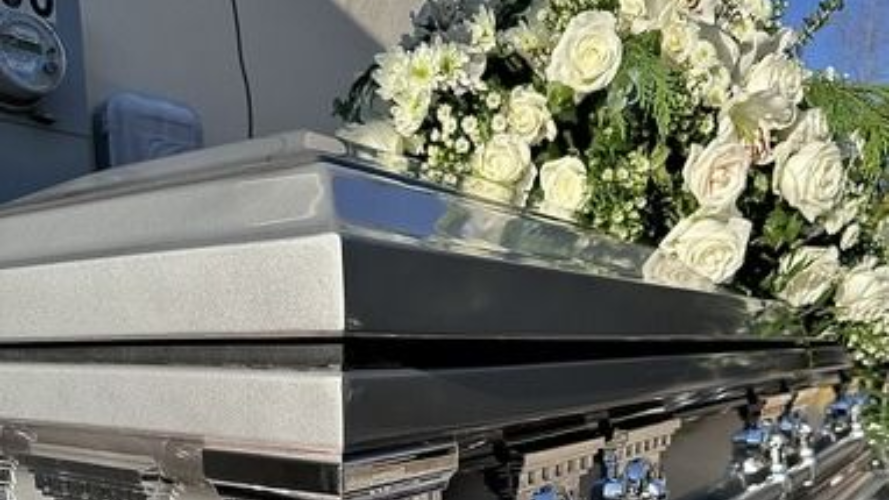 Silver coffin with white rose arrangement at a funeral chapel