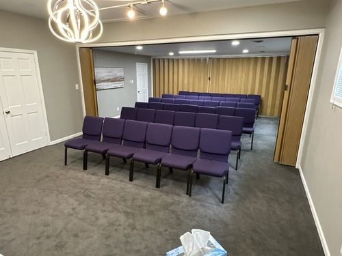 Empty meeting room with rows of purple chairs and gray carpet