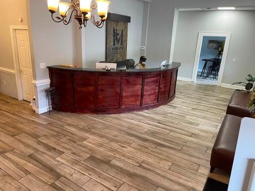 Lobby with curved wooden reception desk, tiled floor, and chandelier lighting.