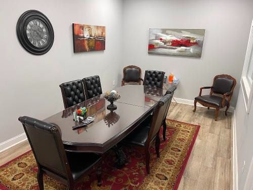 Modern office meeting room with dark table, black chairs, red rug, and wall art