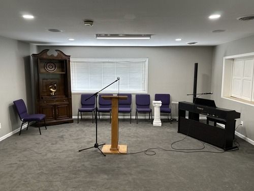 Small meeting room with podium, microphone, purple chairs, and a piano on the right