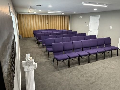 Empty room with rows of purple chairs facing a curtained front wall