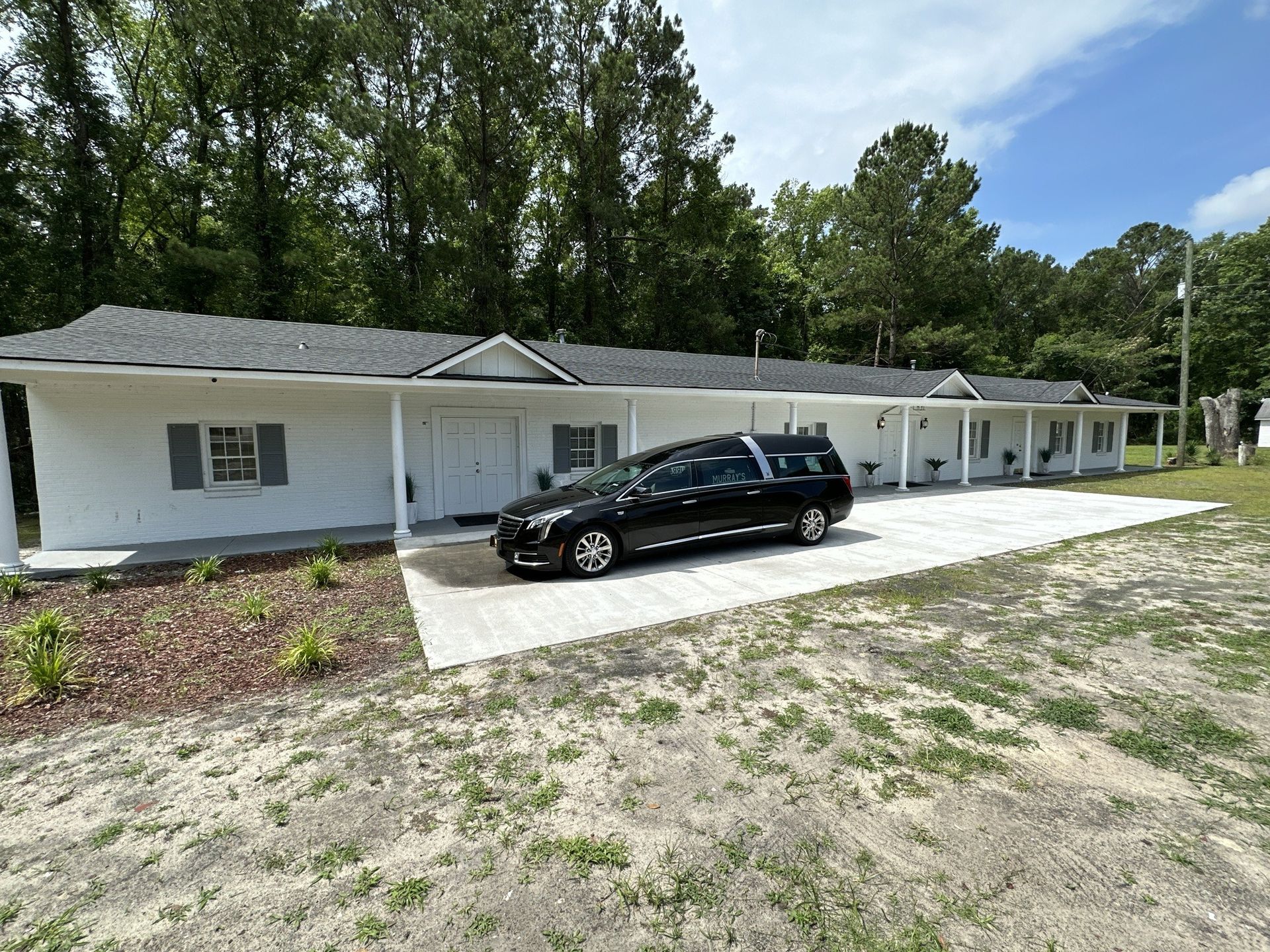 Single-story white house with a black SUV parked on a concrete driveway.