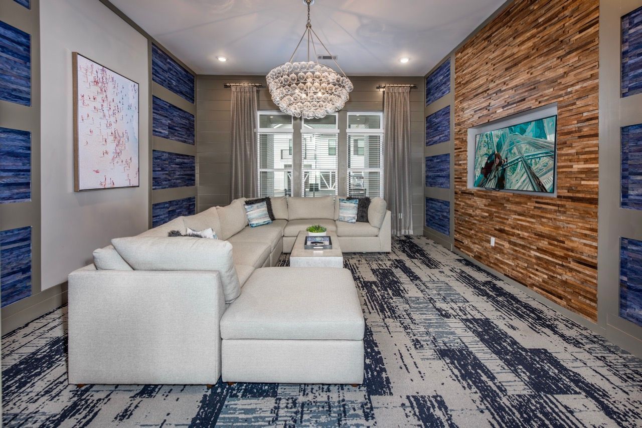 Light-gray sectional sofa in a modern living room with a stone accent wall and a chandelier.