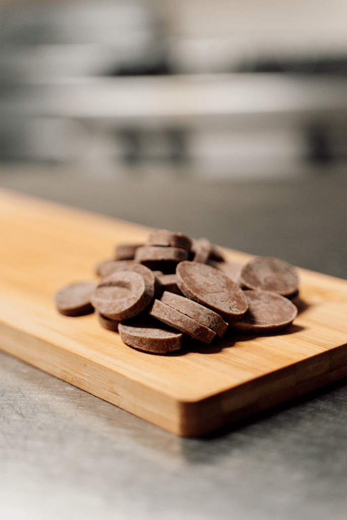 Una pila di gocce di cioccolato su un tagliere di legno.