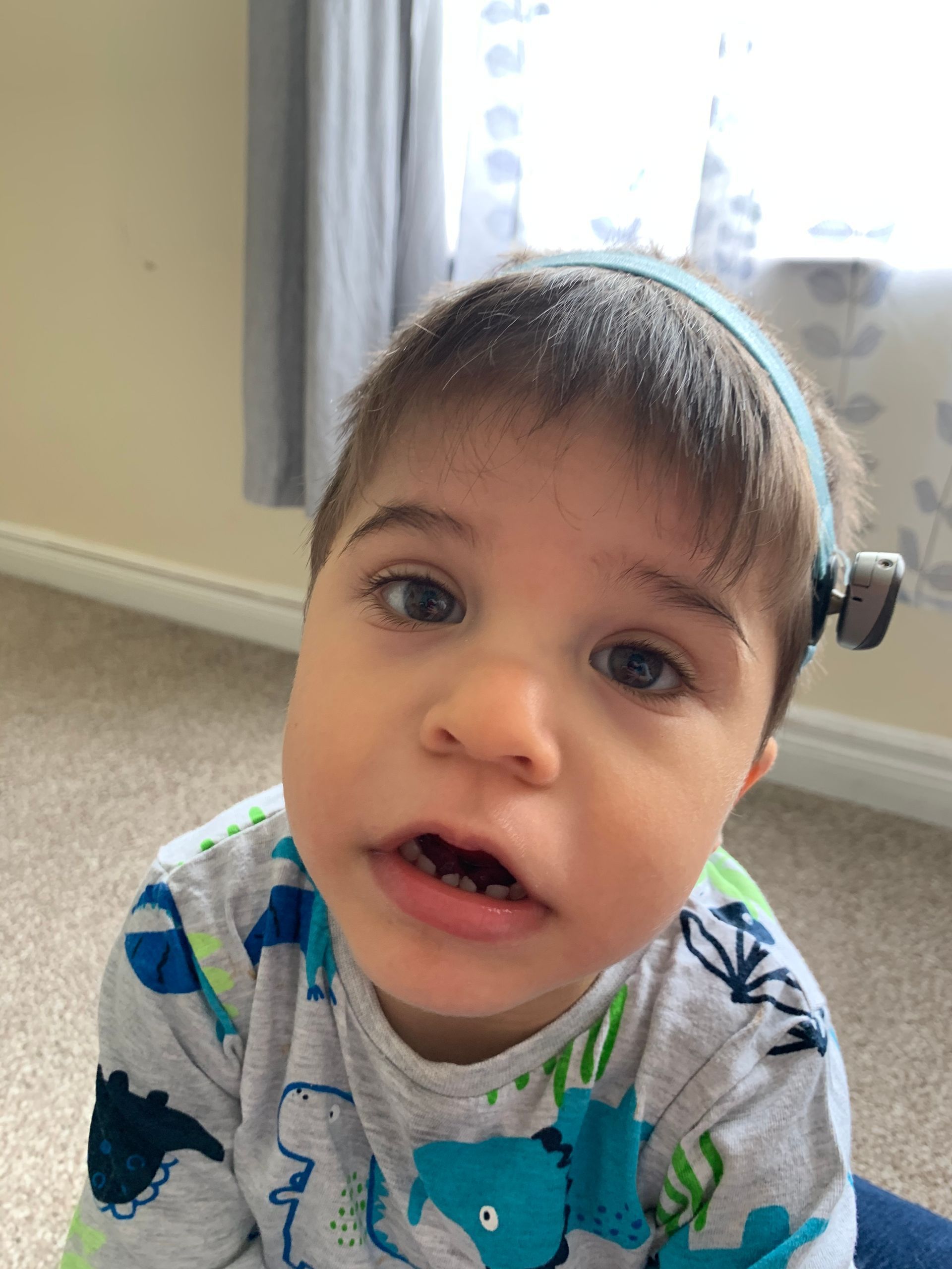 A young boy wearing a headband is looking at the camera.