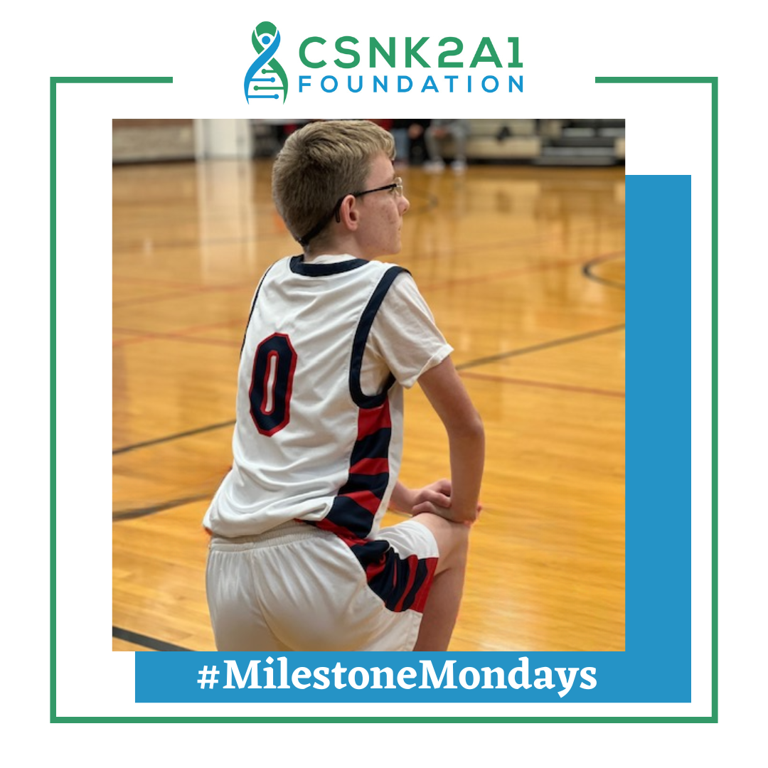 A boy wearing a number 0 jersey is kneeling on a basketball court