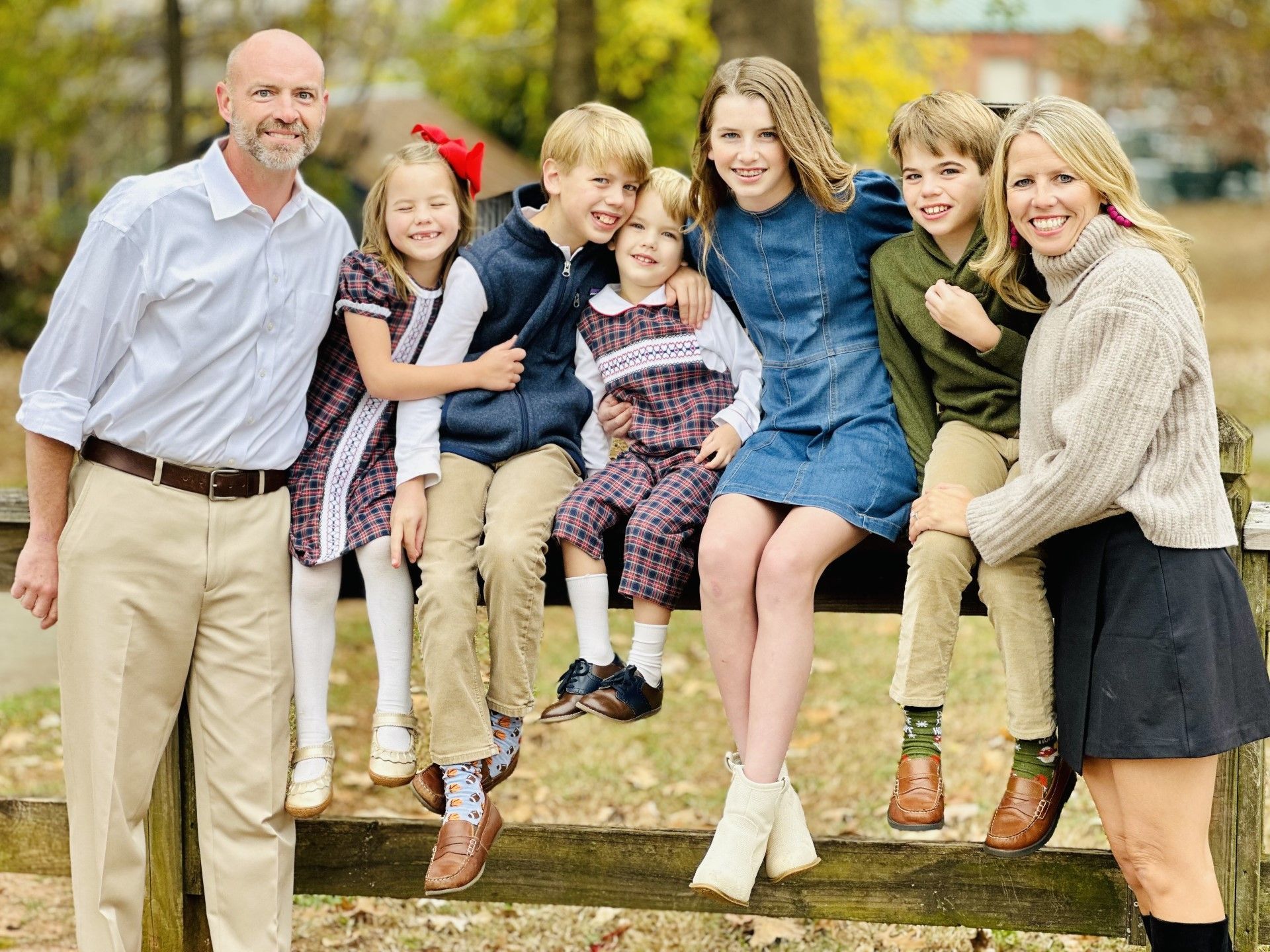 a family is posing for a picture while sitting on a fence