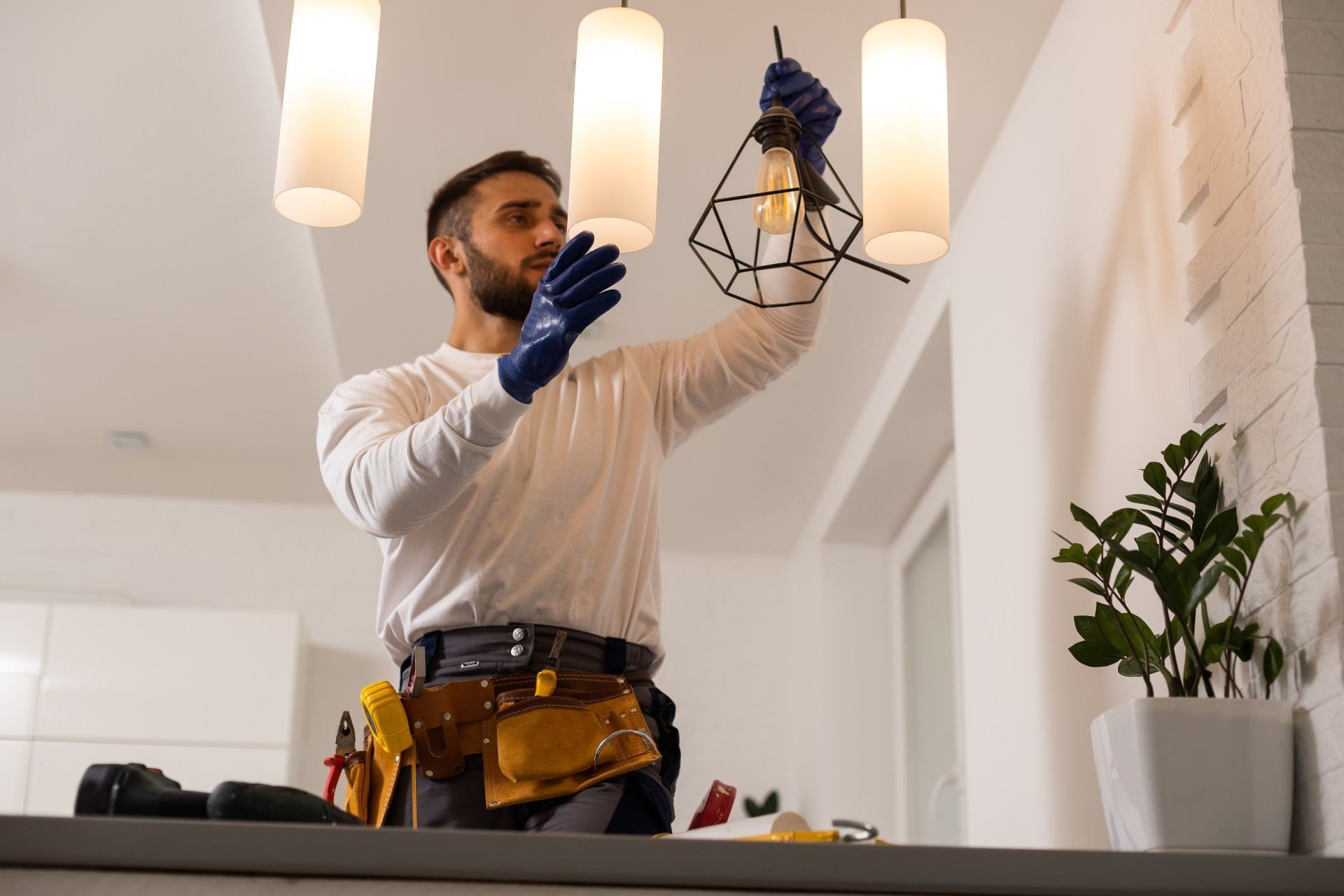 A man is fixing a light fixture in a living room.