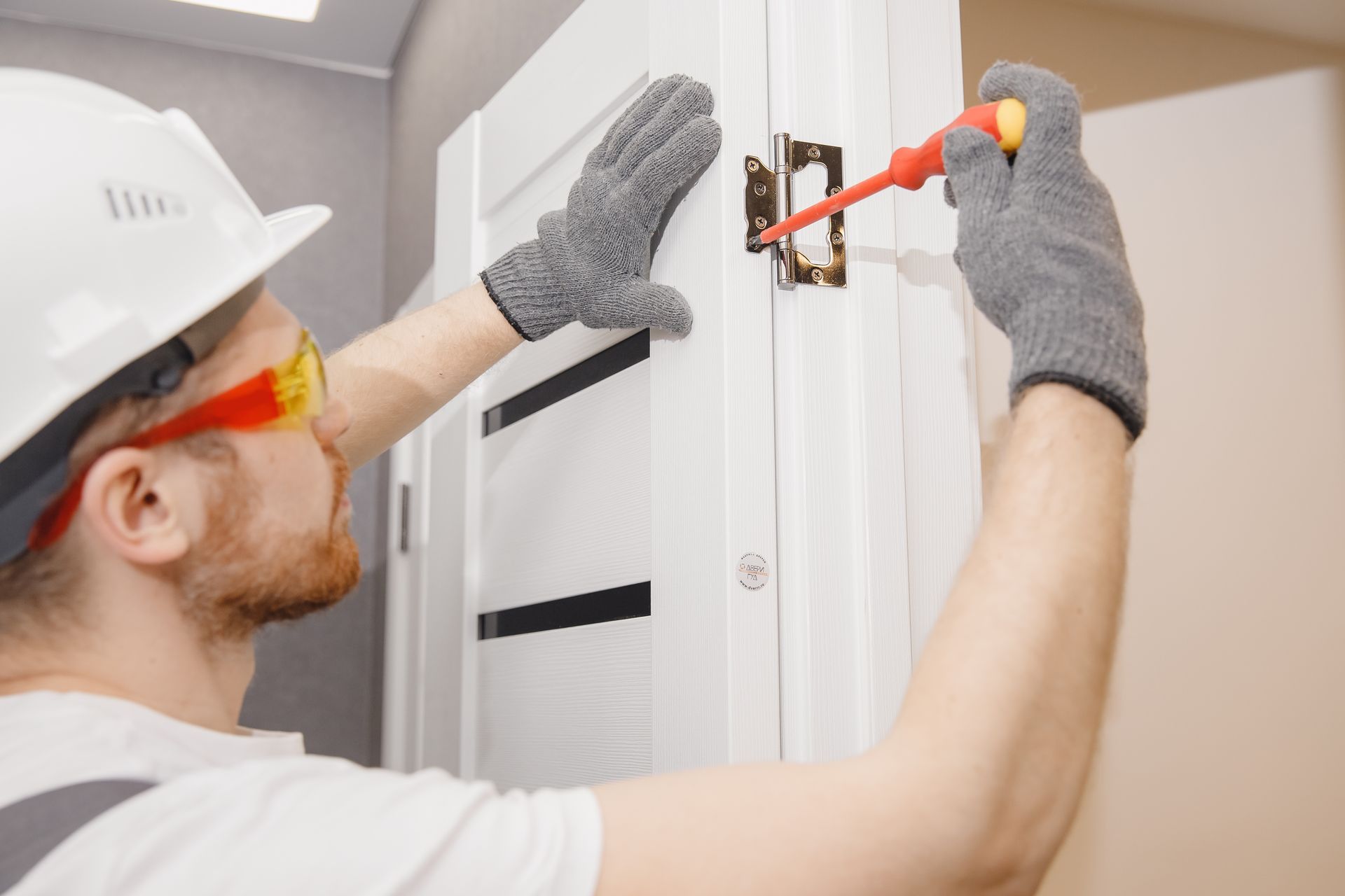A man is fixing a door with a screwdriver.