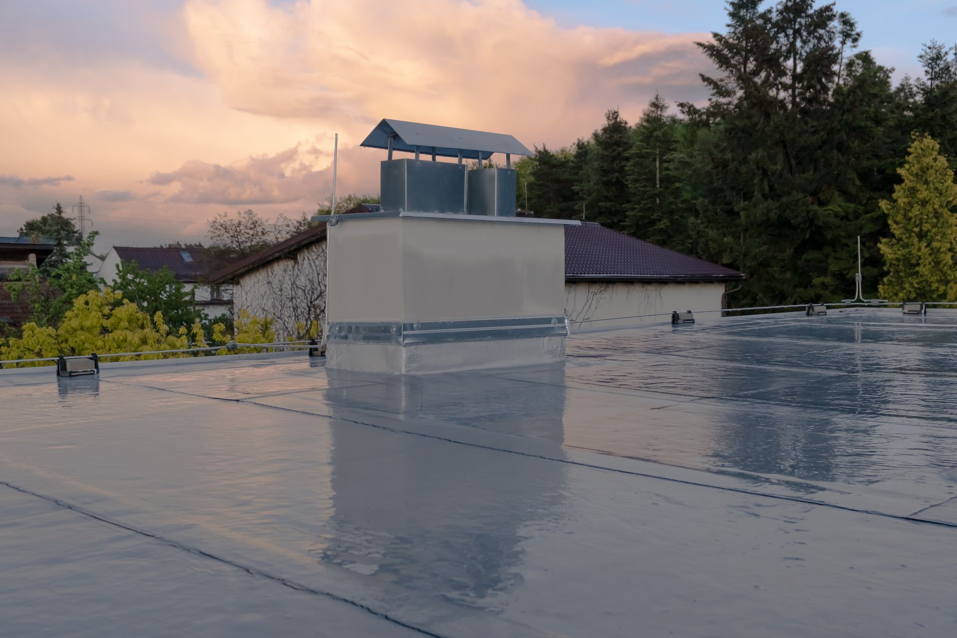 A roof with a chimney on top of it and trees in the background.