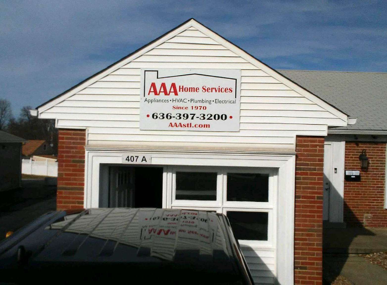 White building with AAA Home Services sign above a garage entrance and parked vehicle in front