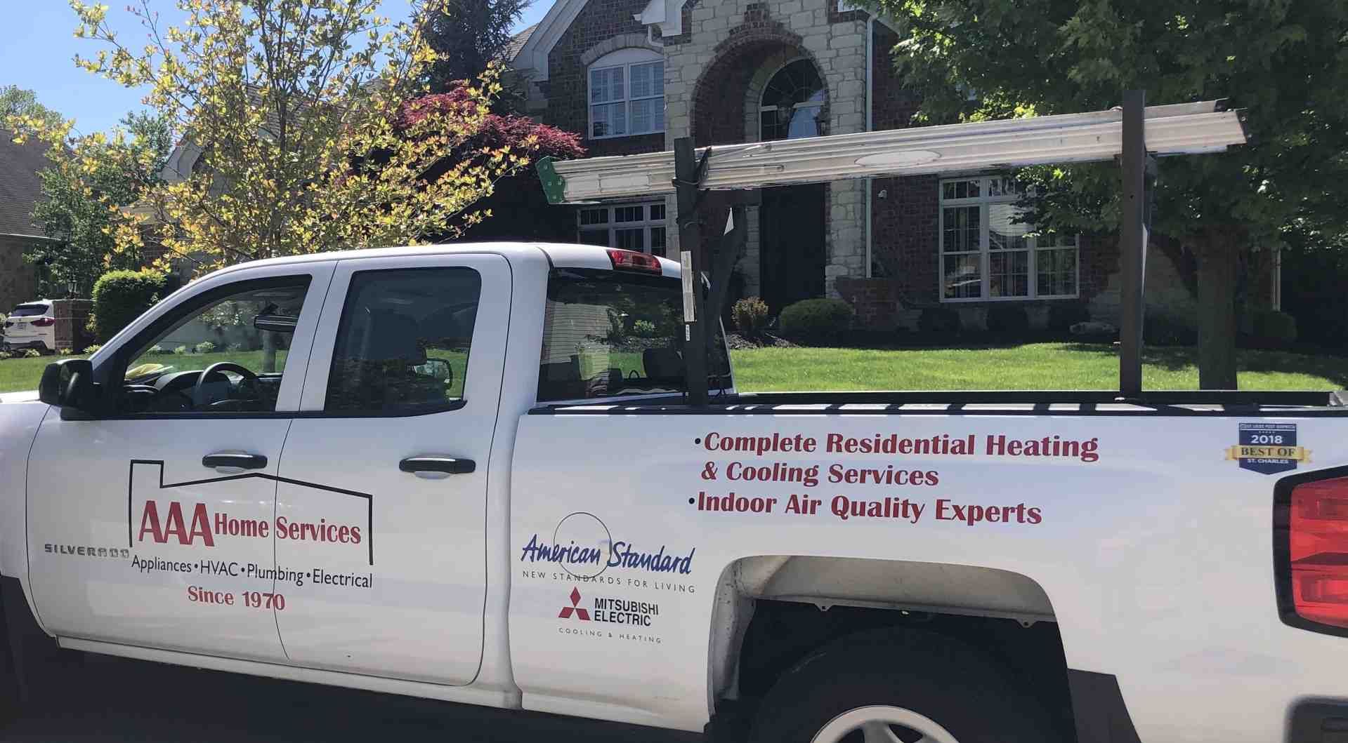 White pickup truck with heating and plumbing company logos parked in a suburban driveway