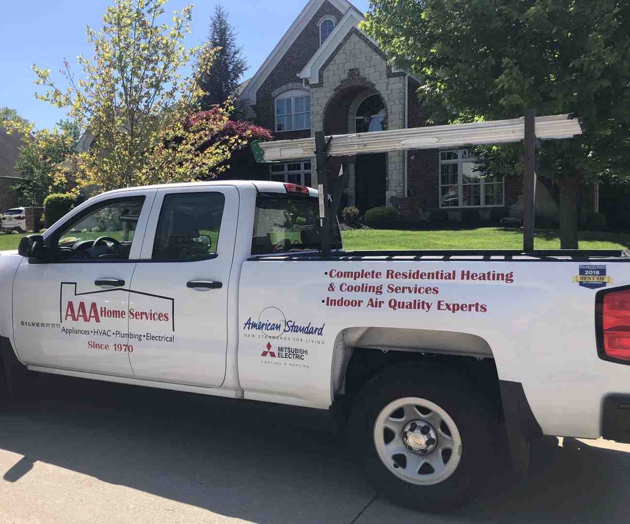 White pickup truck with contractor signage parked in front of a house on a sunny street