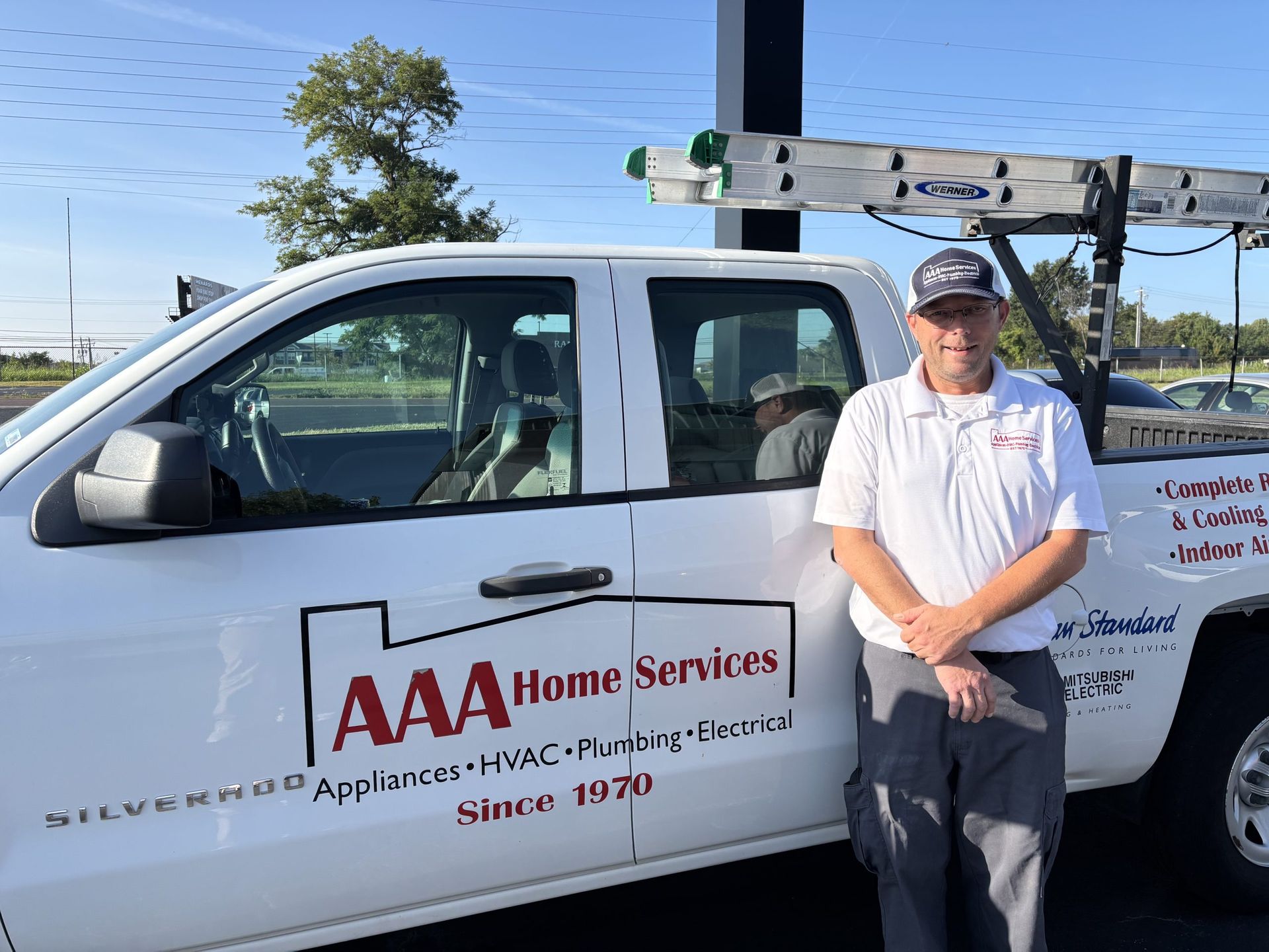 AAA Home Services truck with a technician standing beside it in a parking lot