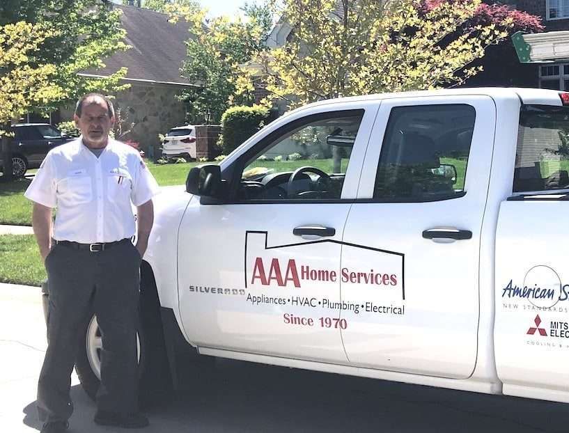 AAA Home Services worker standing beside a white service truck in a sunny driveway