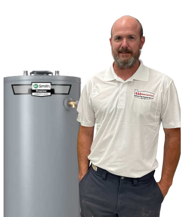 Man standing beside a gray water heater tank, wearing a white polo and dark pants, smiling at the camera