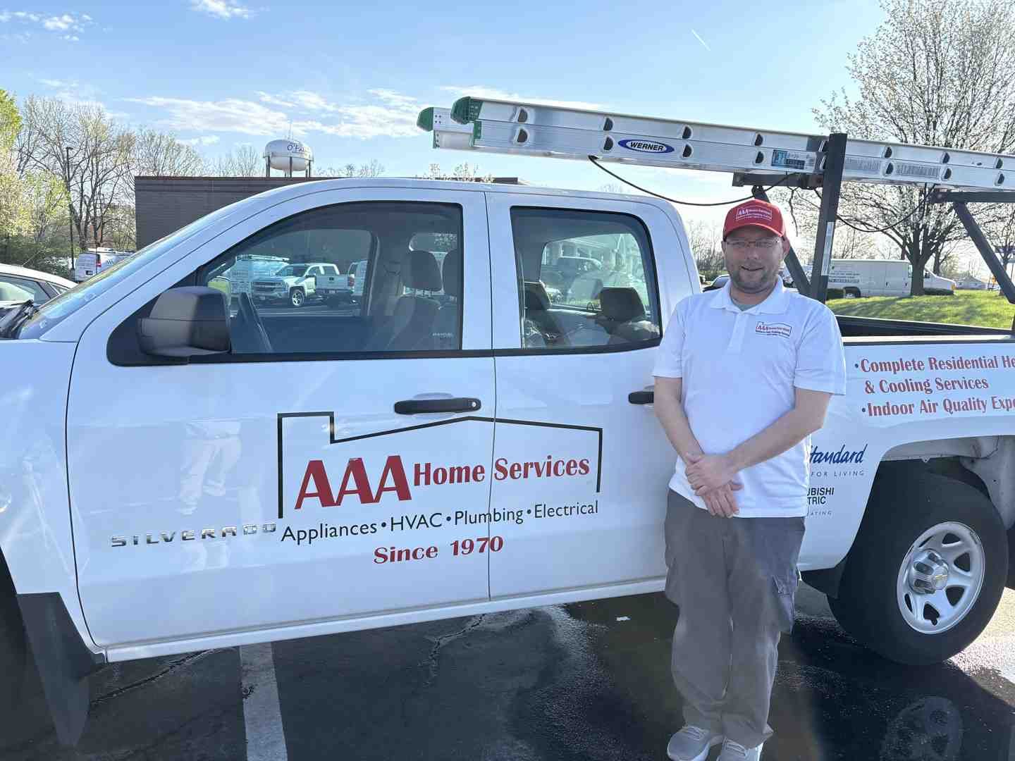 AAA Home Services truck with a worker standing beside it outdoors