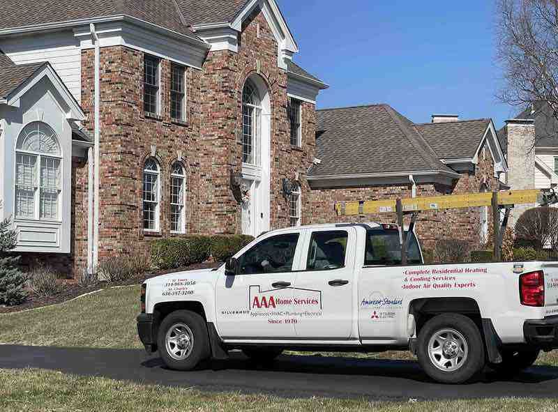 White pickup truck parked in front of a brick house on a sunny day
