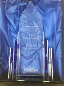 Blue glass award plaque with etched text, flanked by clear vertical panels, on a dark background