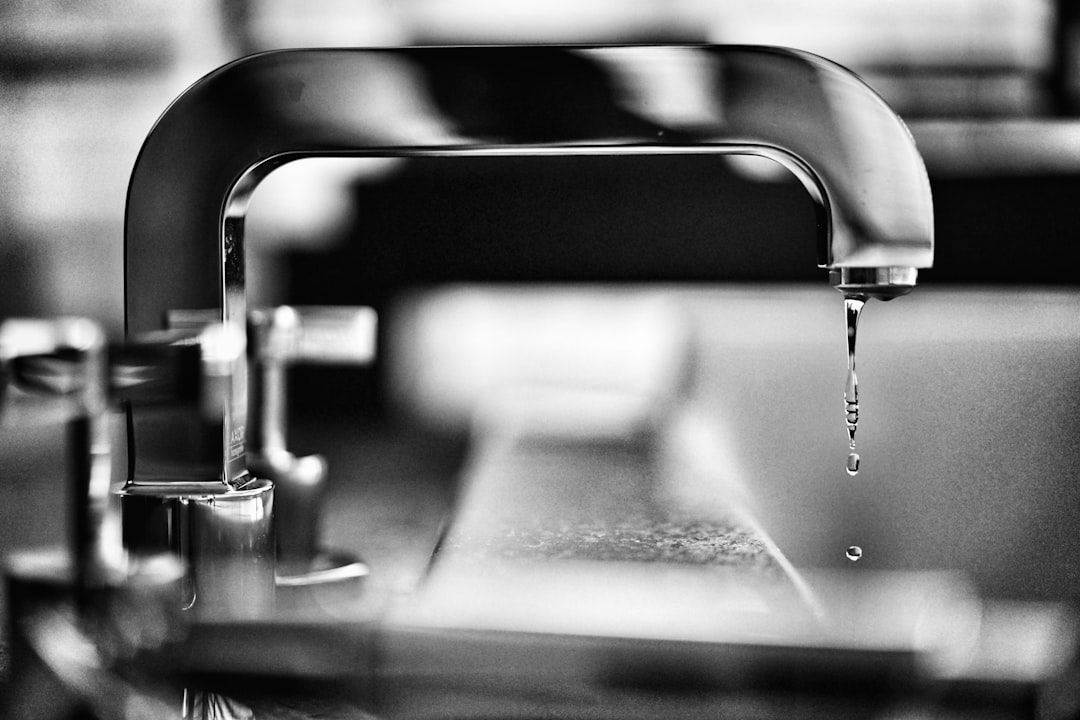 Black-and-white close-up of a faucet dripping water over a sink