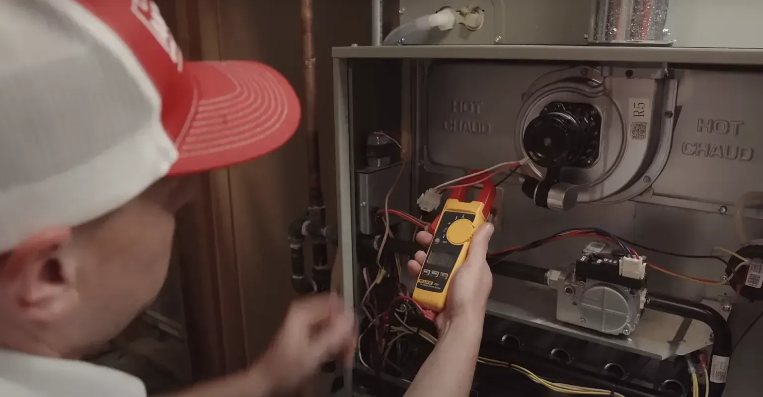 Technician testing wiring inside an open appliance panel with a multimeter
