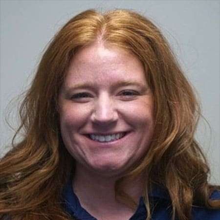 Smiling woman with red hair against a plain gray background