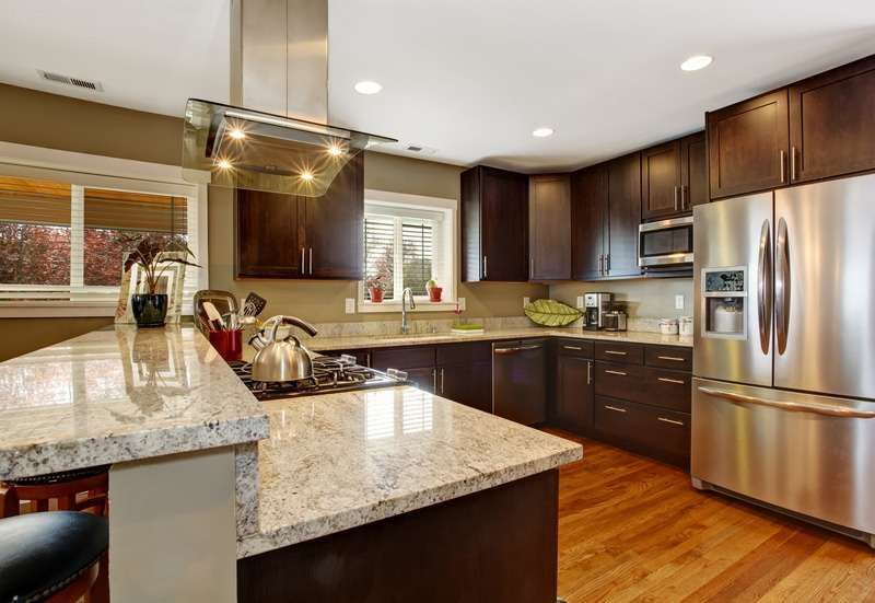 Modern kitchen with granite island, dark wood cabinets, stainless steel appliances, and hardwood floors