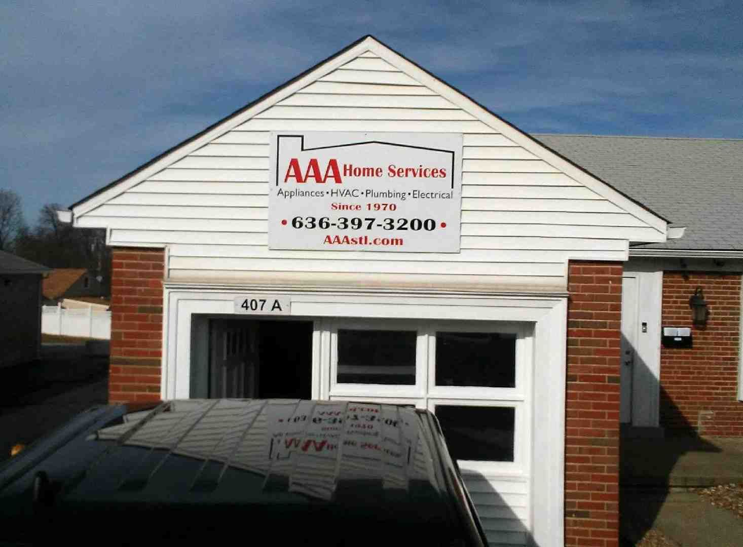 AAA Home Services storefront with white gable, red brick, and phone number sign above the garage entrance
