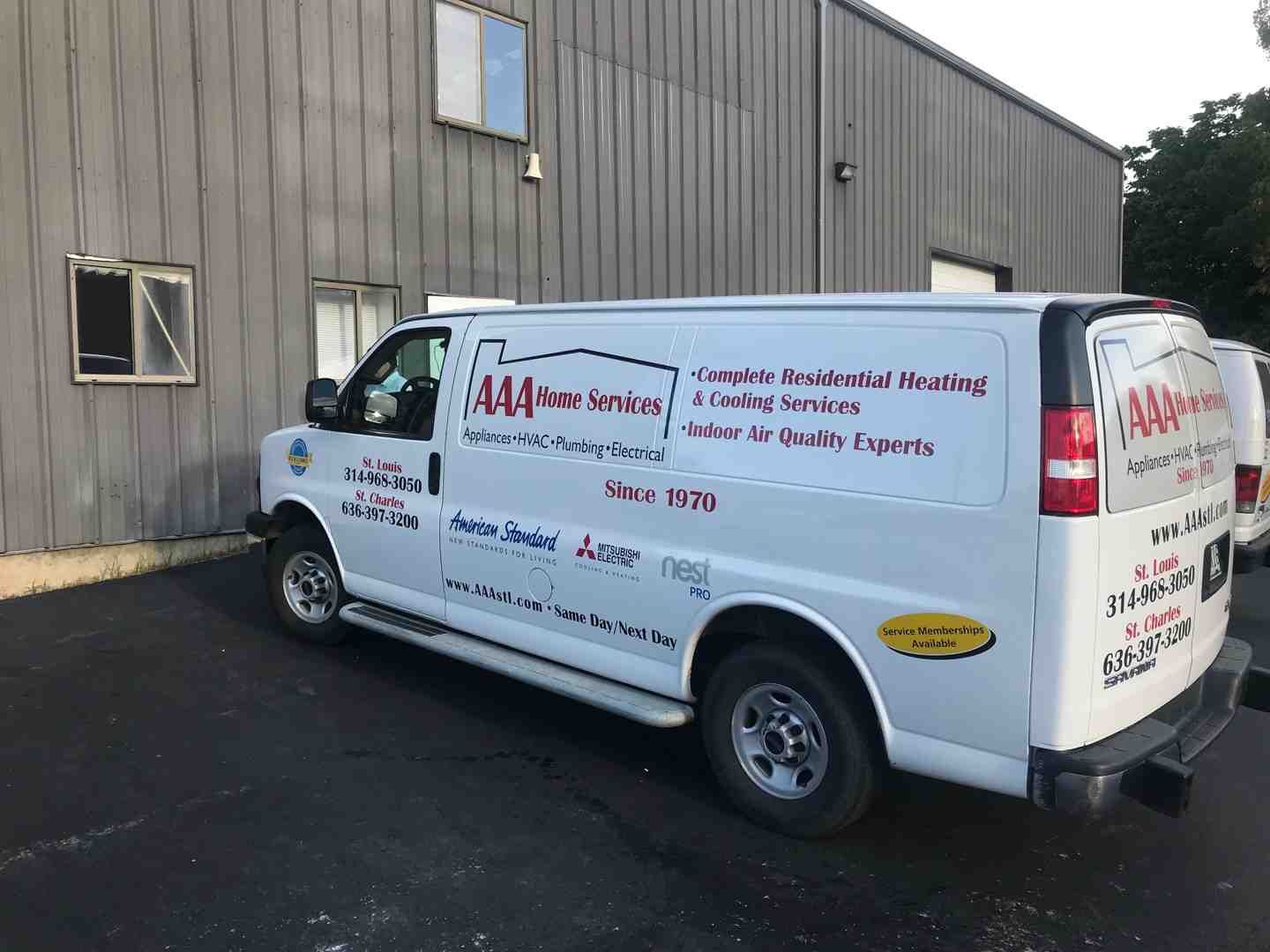 White service van with red lettering parked beside a gray industrial building.