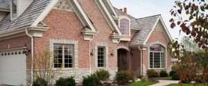 Brick suburban house with gabled roof, front porch, and landscaped shrubs