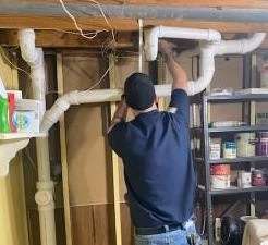 Person installing white PVC pipes in a workshop with shelves of supplies in the background