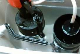 Close-up of two black mechanical parts with white tubing inside a metal tray