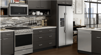 Modern kitchen with stainless steel appliances, dark cabinets, and a large window overlooking a city view