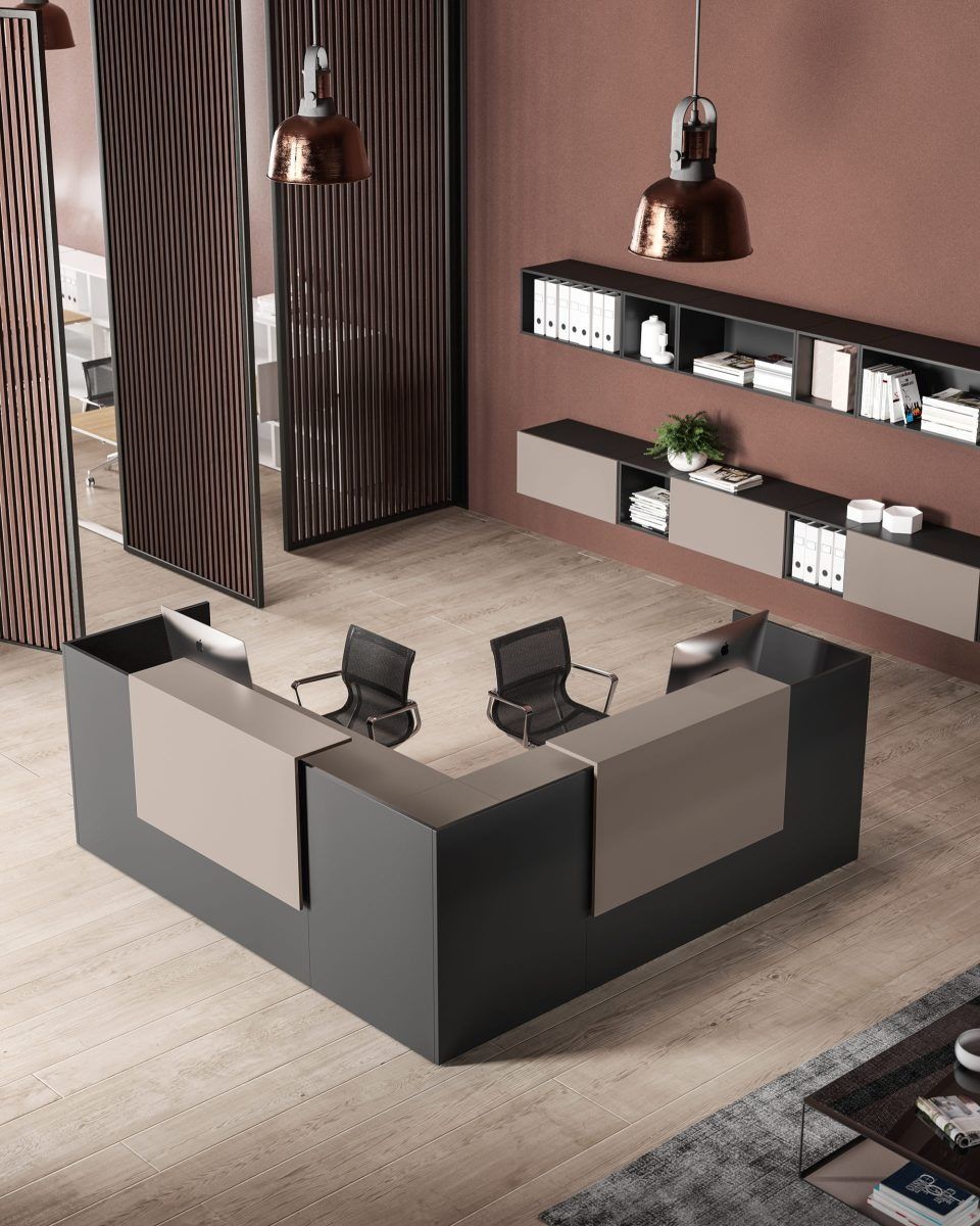 Un moderno bancone reception a forma di L nei toni del grigio antracite e del beige, con due sedie da ufficio, mensole e lampade a sospensione.