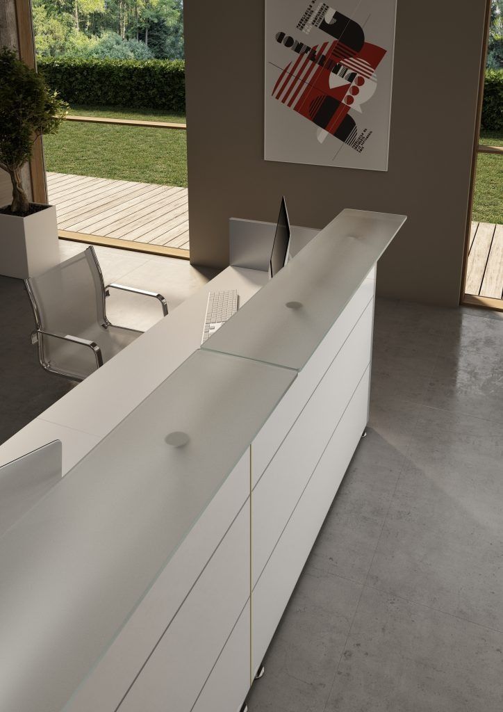 Un moderno bancone reception bianco con piano in vetro satinato in un ufficio minimalista con ampie finestre.