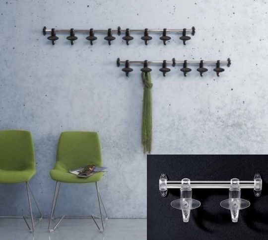 Sopra una parete grigia, sopra due sedie verdi, sono appesi due appendiabiti metallici a muro con ganci scuri, come mostrato in un primo piano.