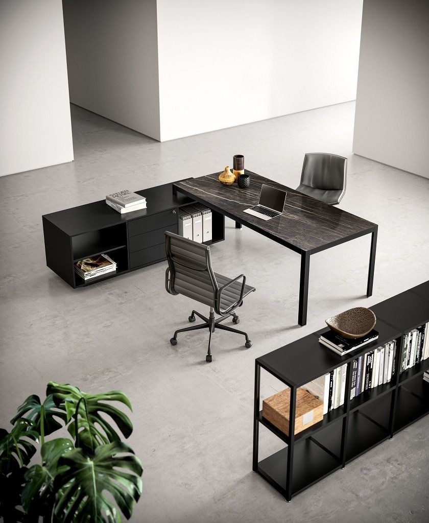 Un set da ufficio moderno e minimalista con scrivania in pietra scura, mensole nere e due sedie ergonomiche su un pavimento in cemento.