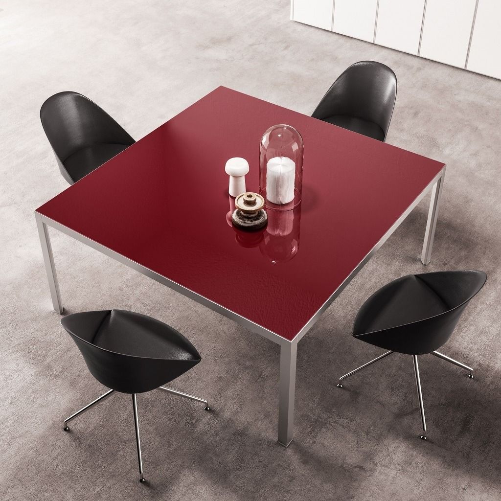 Un moderno tavolo da pranzo quadrato rosso, circondato da quattro sedie nere su un pavimento grigio, con candele decorative al centro.