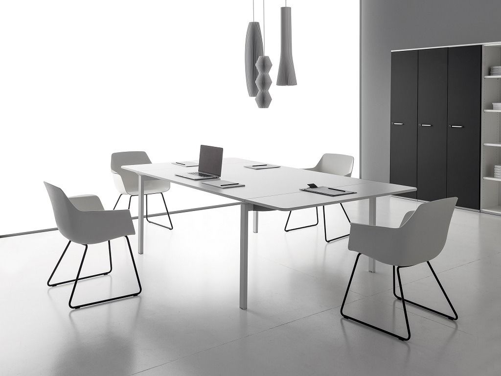 Un ufficio minimalista con un tavolo da conferenza bianco, quattro sedie con struttura nera e lampade a sospensione.