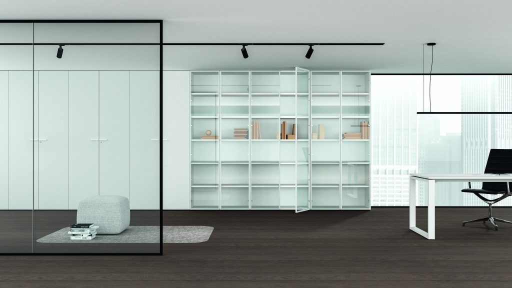 Un ufficio moderno e minimalista con mobili contenitori bianchi, pareti divisorie in vetro, pavimento in legno scuro, scrivania e sedia.