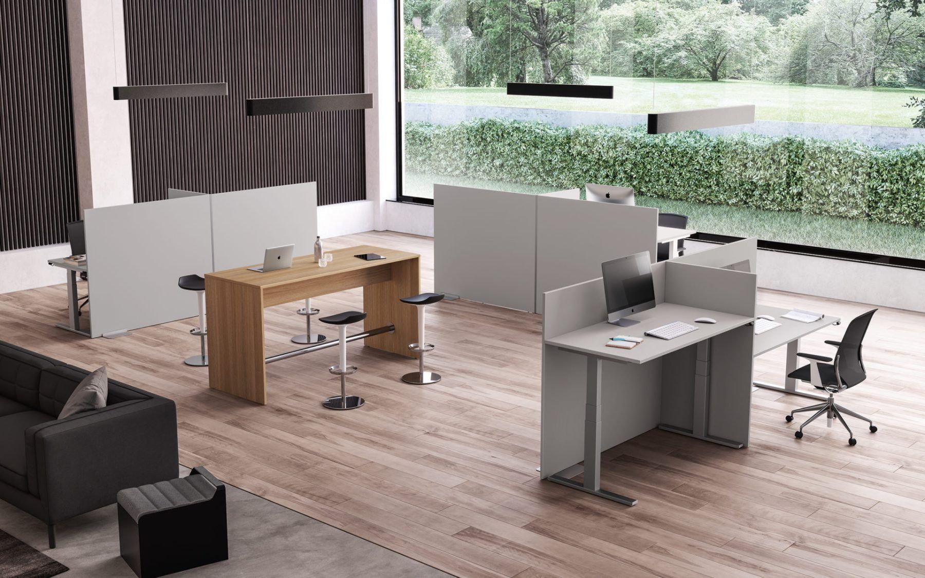 Moderno spazio di lavoro per ufficio con tavoli regolabili in altezza in legno, scrivanie individuali grigie e un divano su un pavimento in legno.