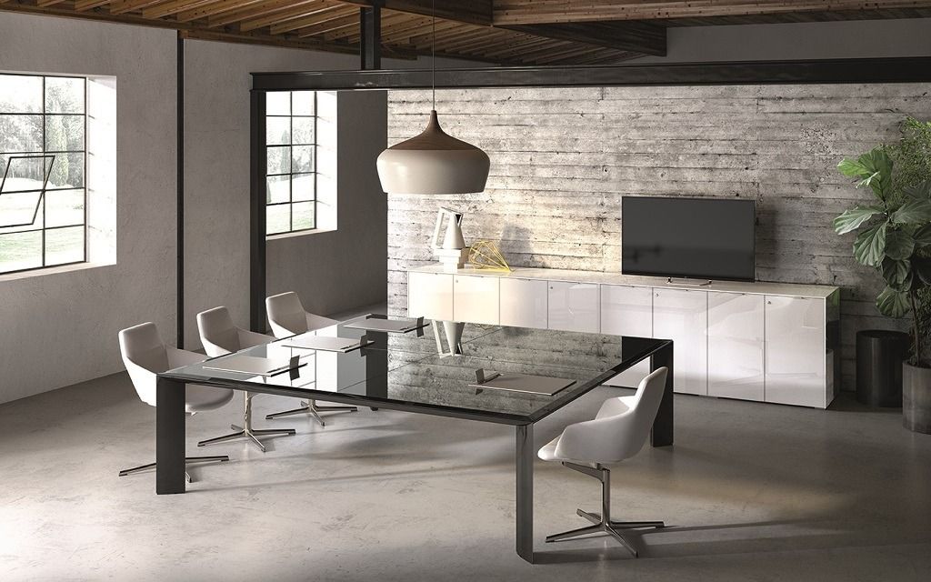 Sala conferenze moderna con un grande tavolo in vetro scuro, sedie girevoli bianche, una parete con finitura effetto pietra e un mobile porta TV.