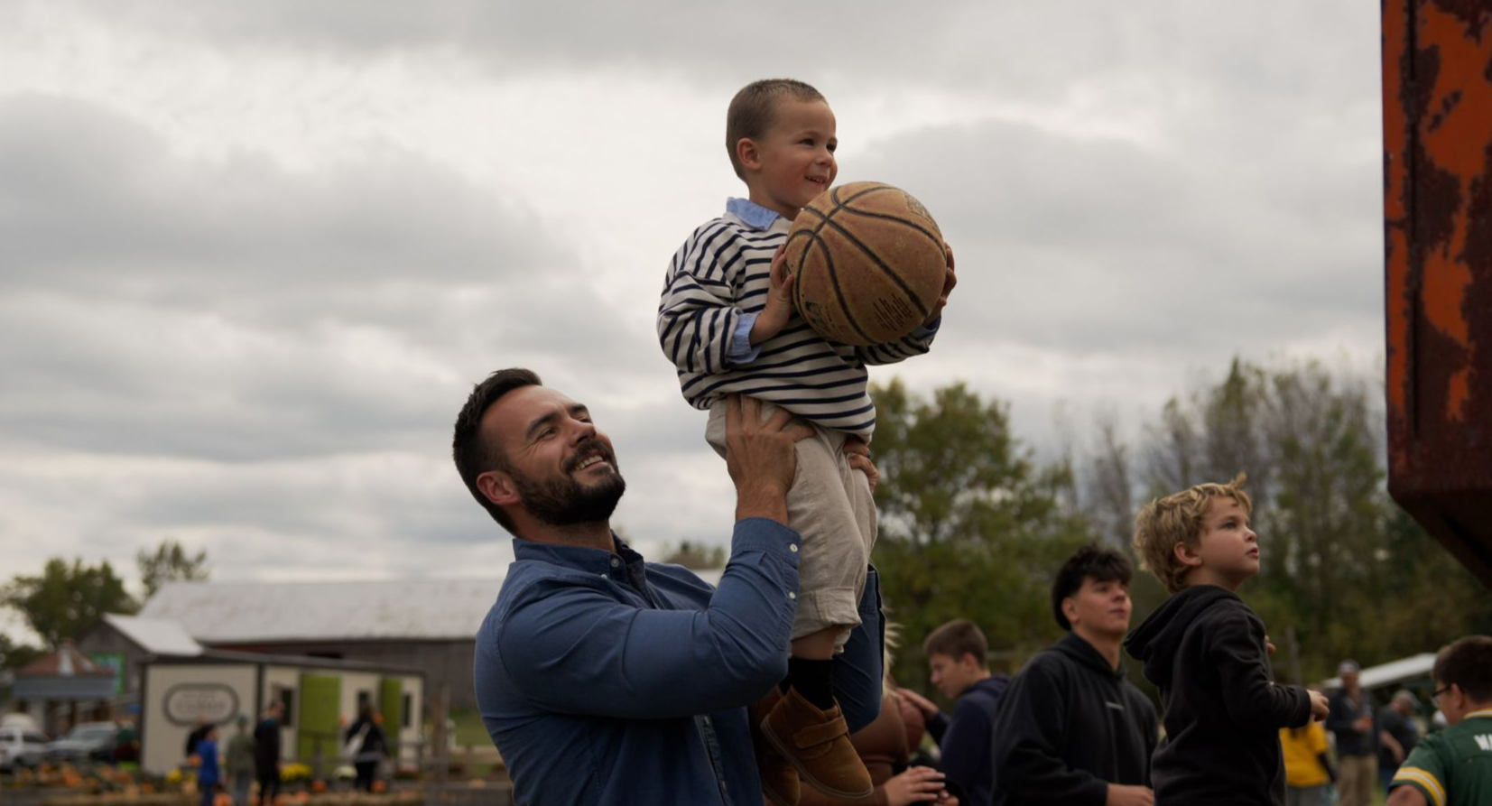 Father lifting his son with a basketball during a community event filmed for Fox Cities CVB tourism video production in Wisconsin.